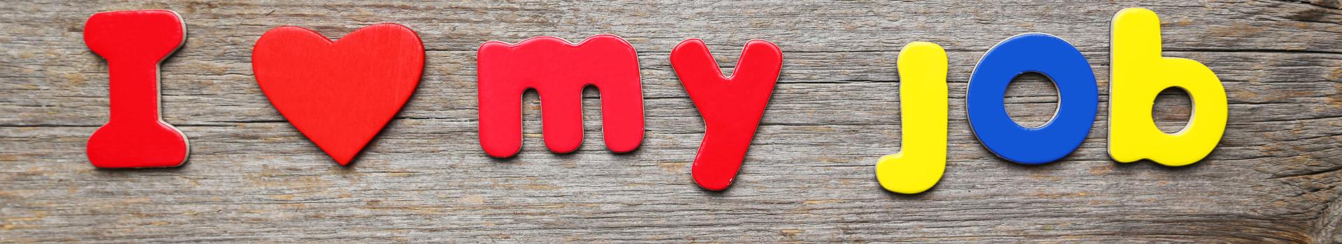 Letters spelling 'I love my job' on wood background
